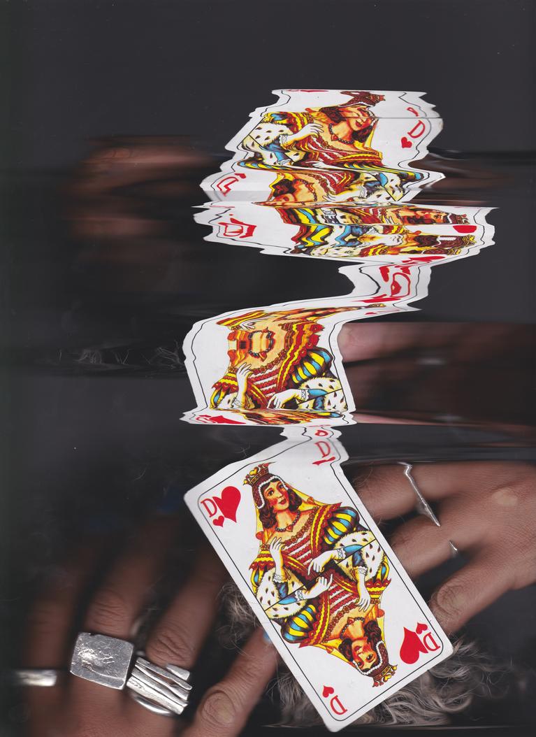 Image de cartes distordues tenues par une paire de main sur les doigts de laquelle on voit de grosses bagues argentées