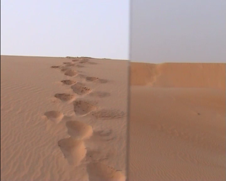 Vue d'une dune de désert à hauteur d'homme, dans la pente, en montant. Des empreintes de pas remplissent le cadre depuis le bas jusqu'à l'horizon qui est à quelques mètres seulement. Dans la  