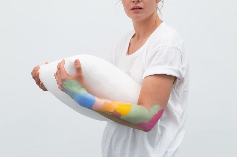 Une femme avec de la peinture sur le bras porte une sculpture blanche