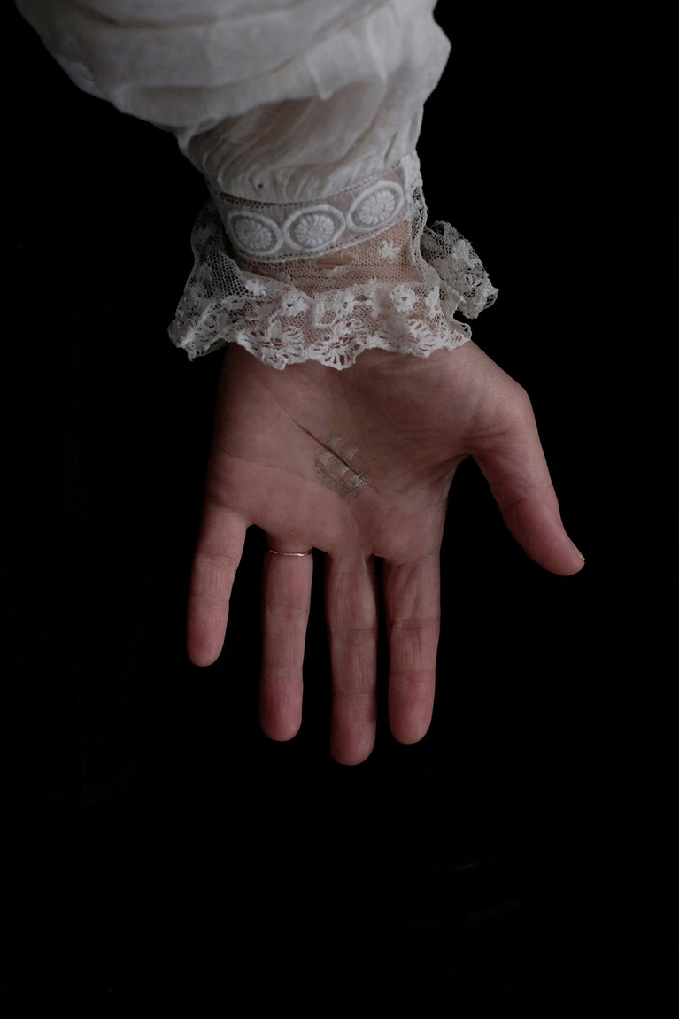 Sur fond noir, une main de femme, avec une chemise en dentelle