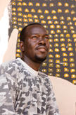 Portrait d'Amadou Sanogo à Bamako, devant une toile.